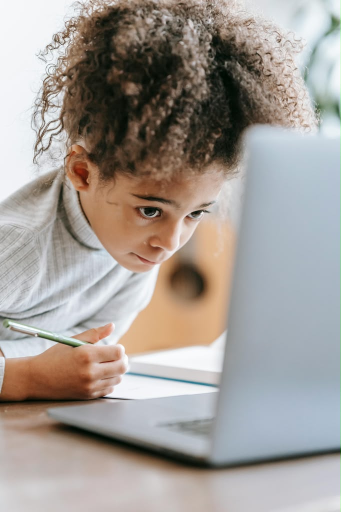 Young girl focused on writing at her laptop
